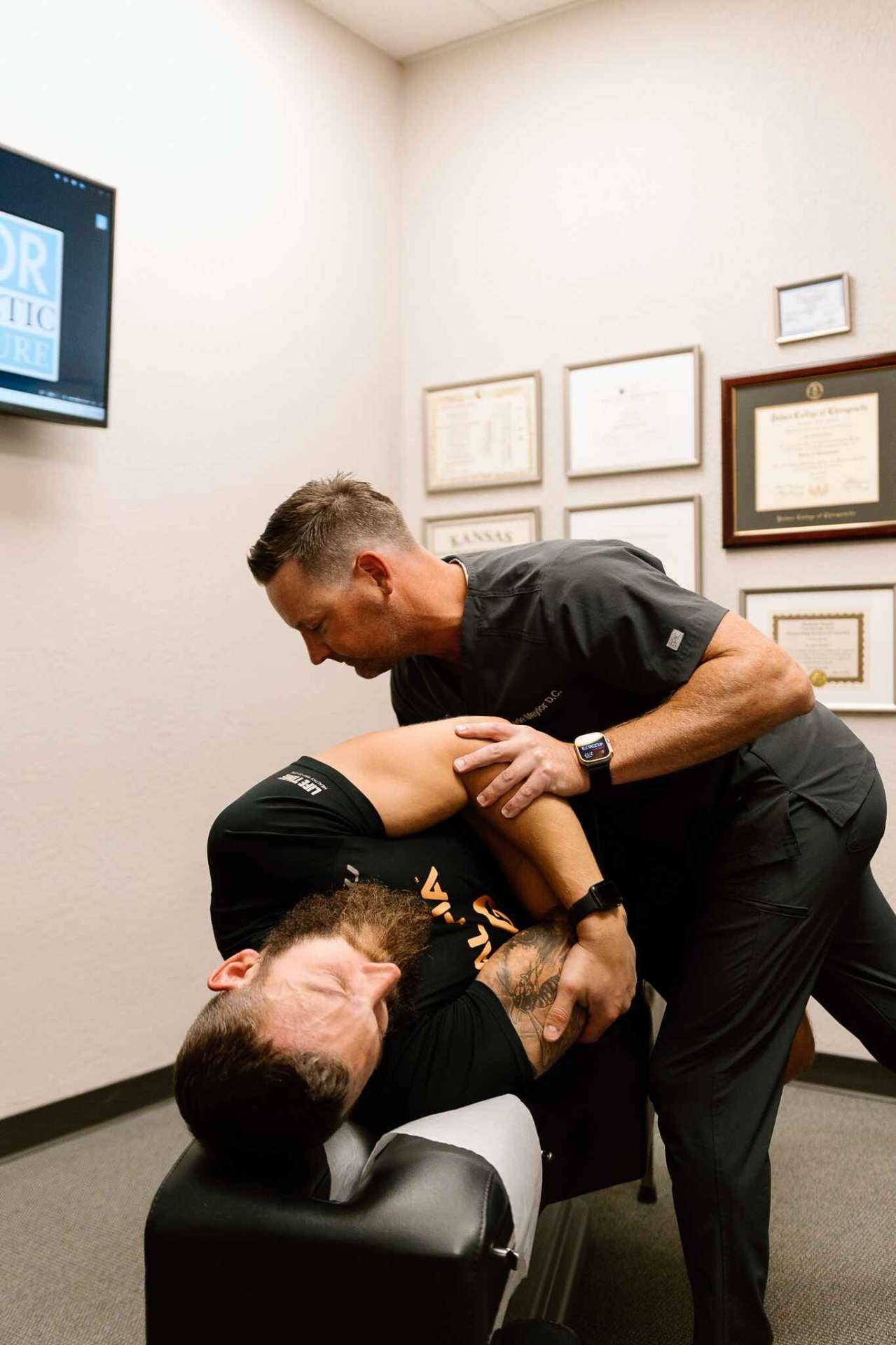 Chiropractor performing adjustment on patient in treatment room