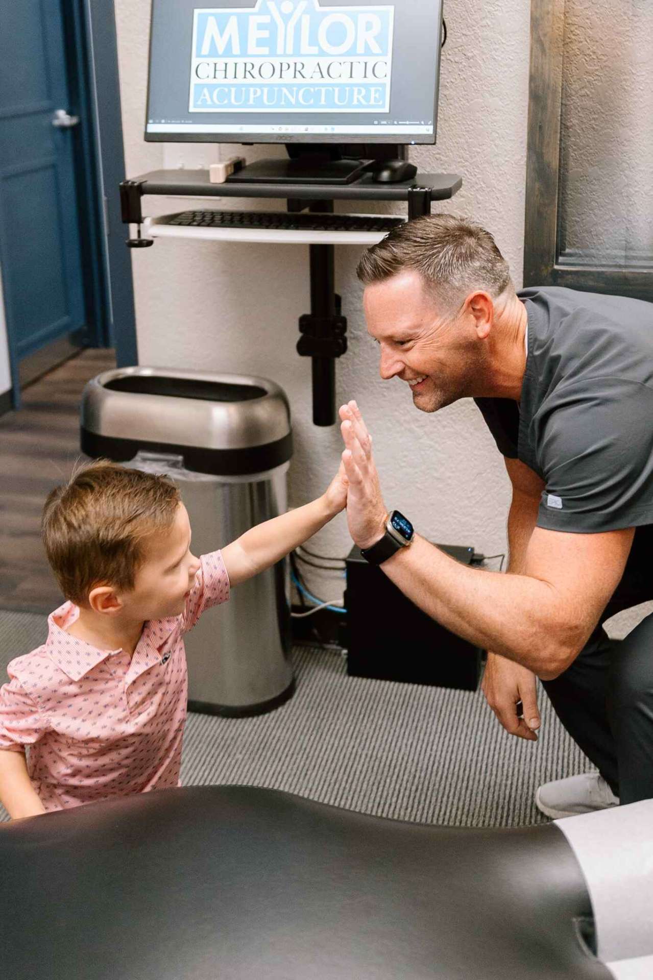 Dr. Meylor giving a high-five to a young patient in the office